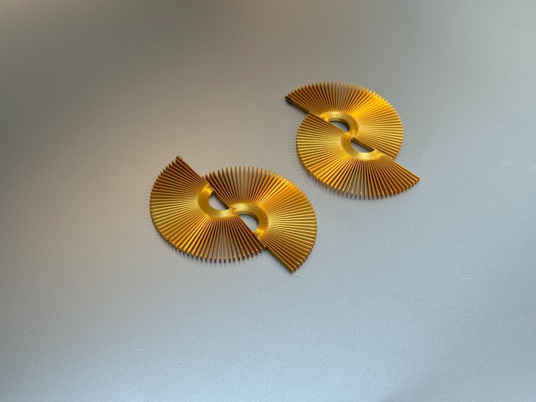 Artisan gold fan-shaped earrings with geometric cutouts on a light grey background