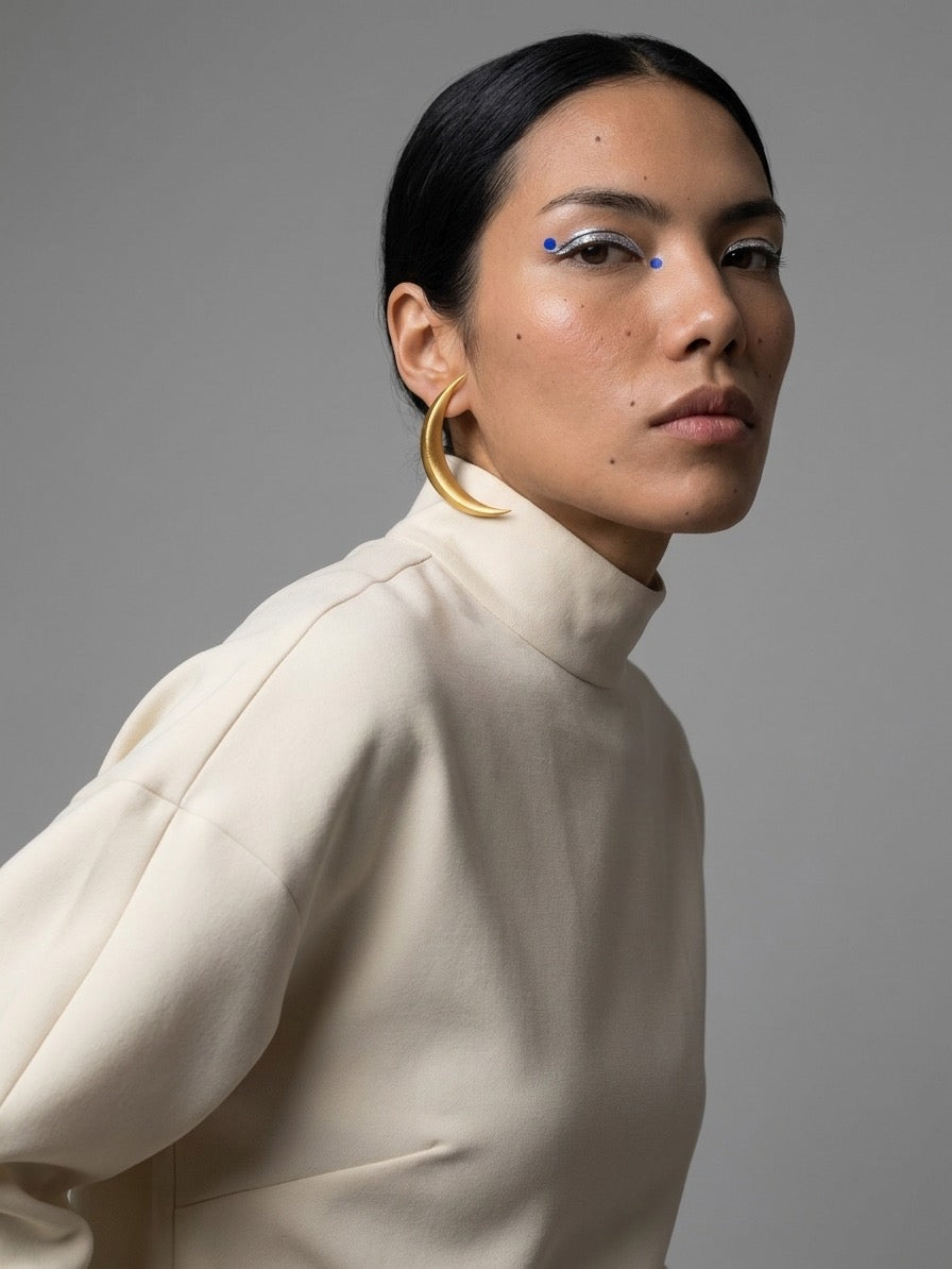 Boucles d’oreilles La Lune dorées portées avec un haut crème