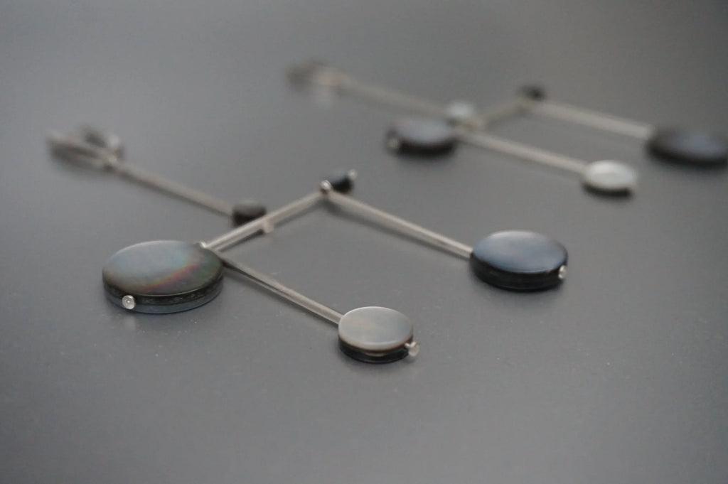 Modern geometric dangle earrings with black and gray circular accents on metal rods