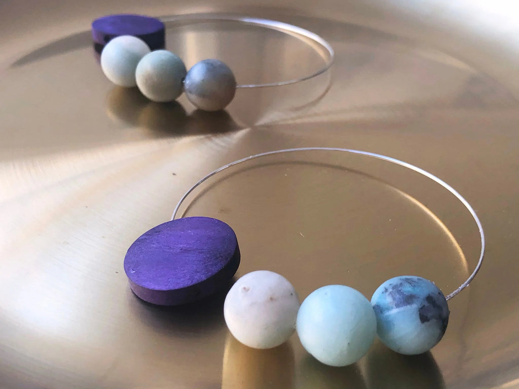 Artisanal bangle bracelets with purple, blue, and cream round beads on gold background