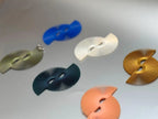 Colorful modern fan-shaped earrings in blue, ivory, green, gold, and peach on a gray background