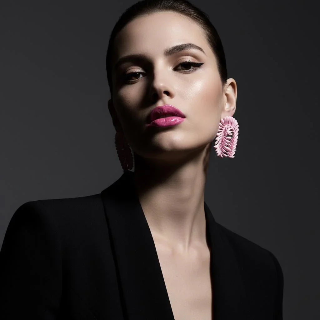 Woman wearing statement pink earrings and a black blazer, elegant artisan jewelry