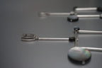 Modern silver and black geometric earrings with round accents on a matte grey surface