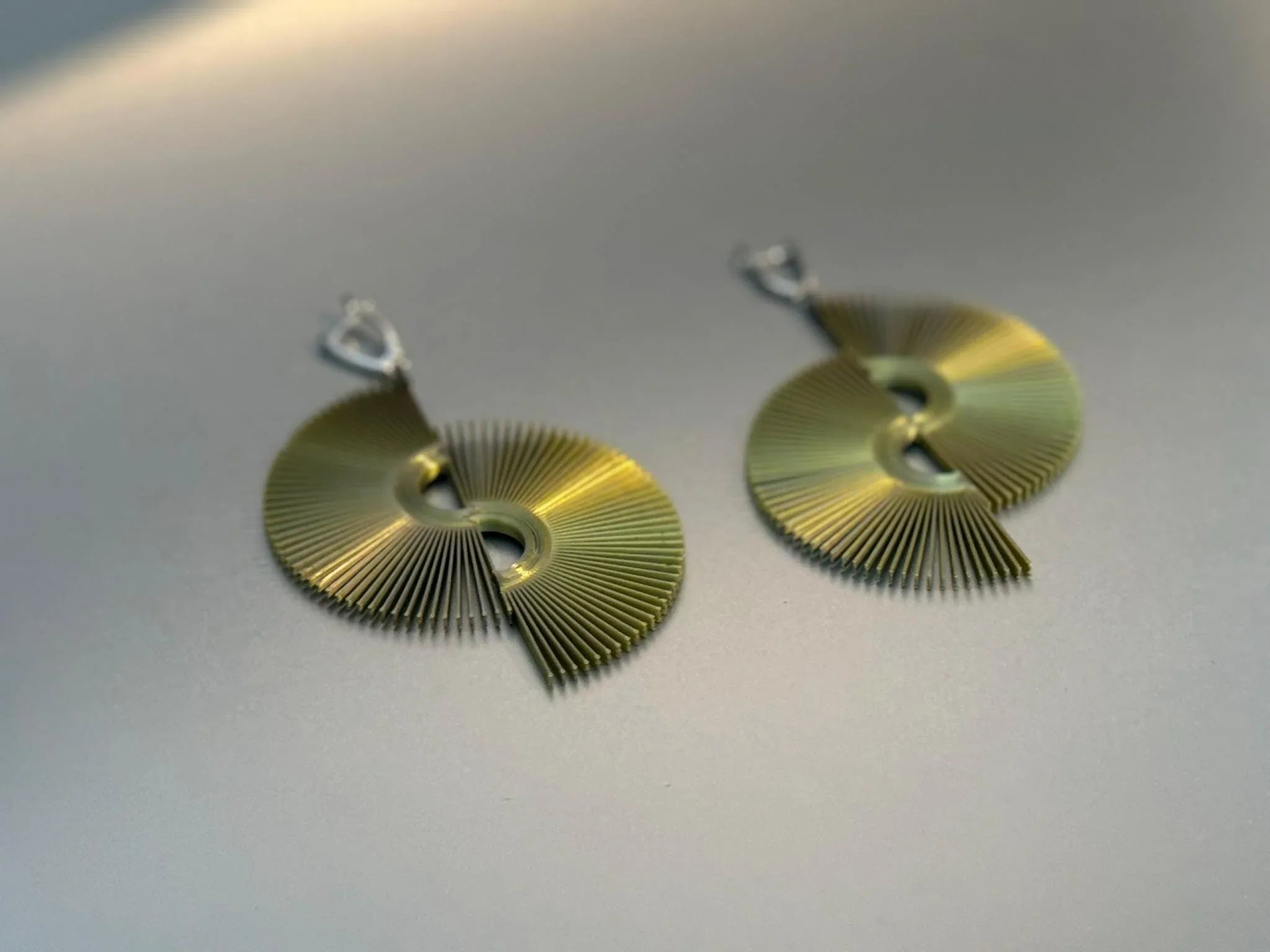 Contemporary gold-tone fan-shaped earrings with geometric cutout design on a neutral background.