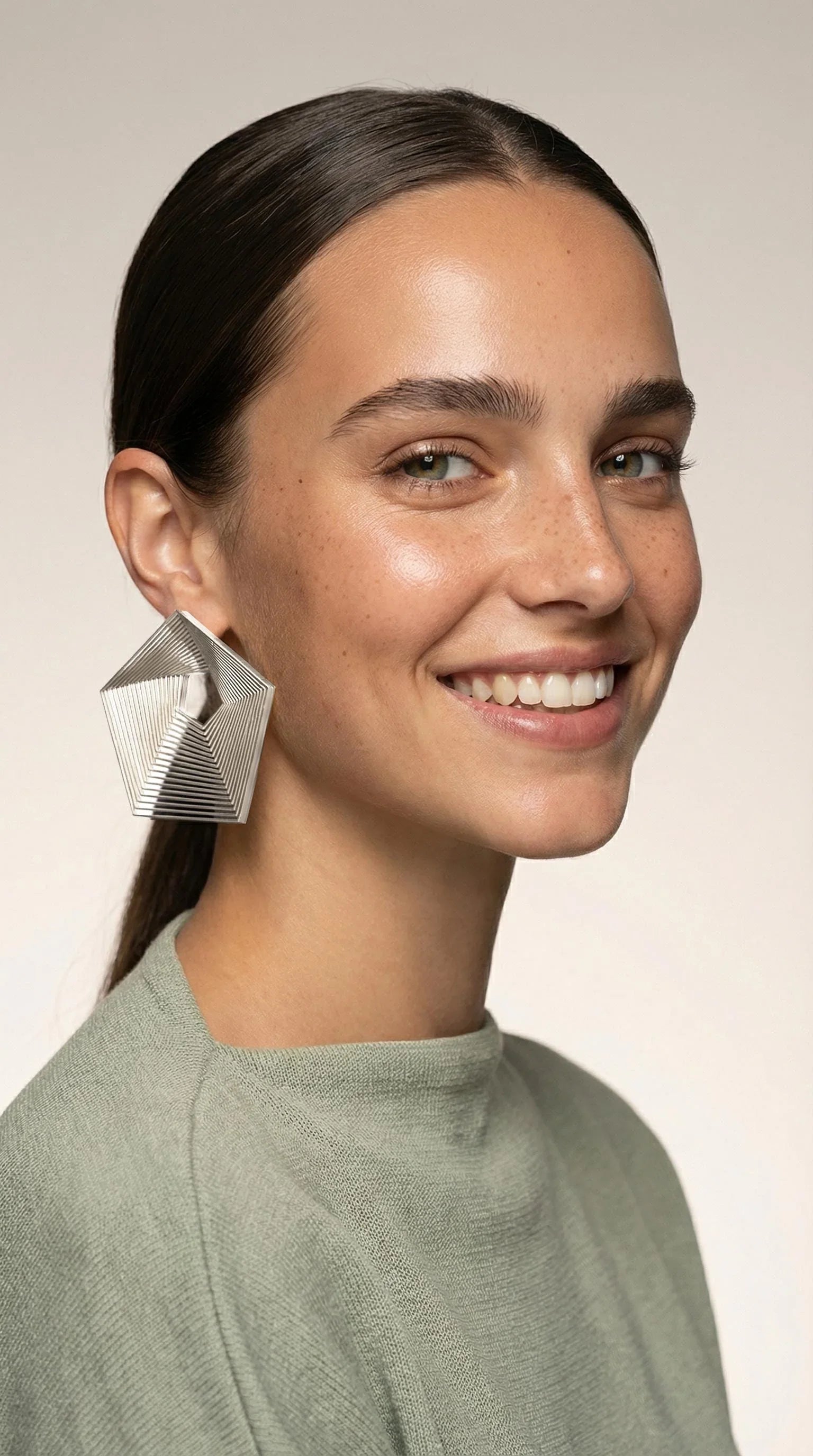 Woman modeling geometric silver statement earring with artistic, modern design