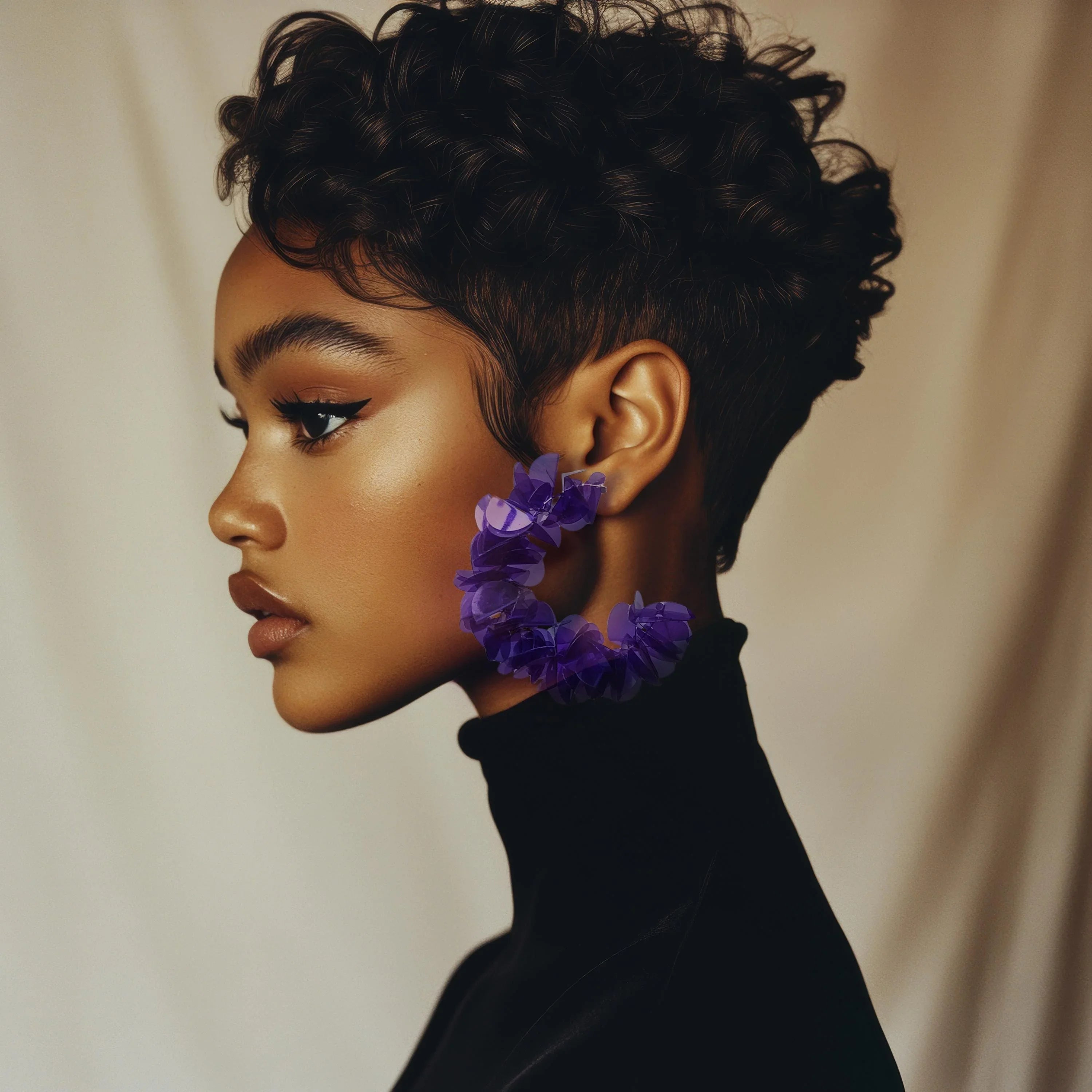 Woman wearing large purple floral statement earrings, modern jewelry, neutral background