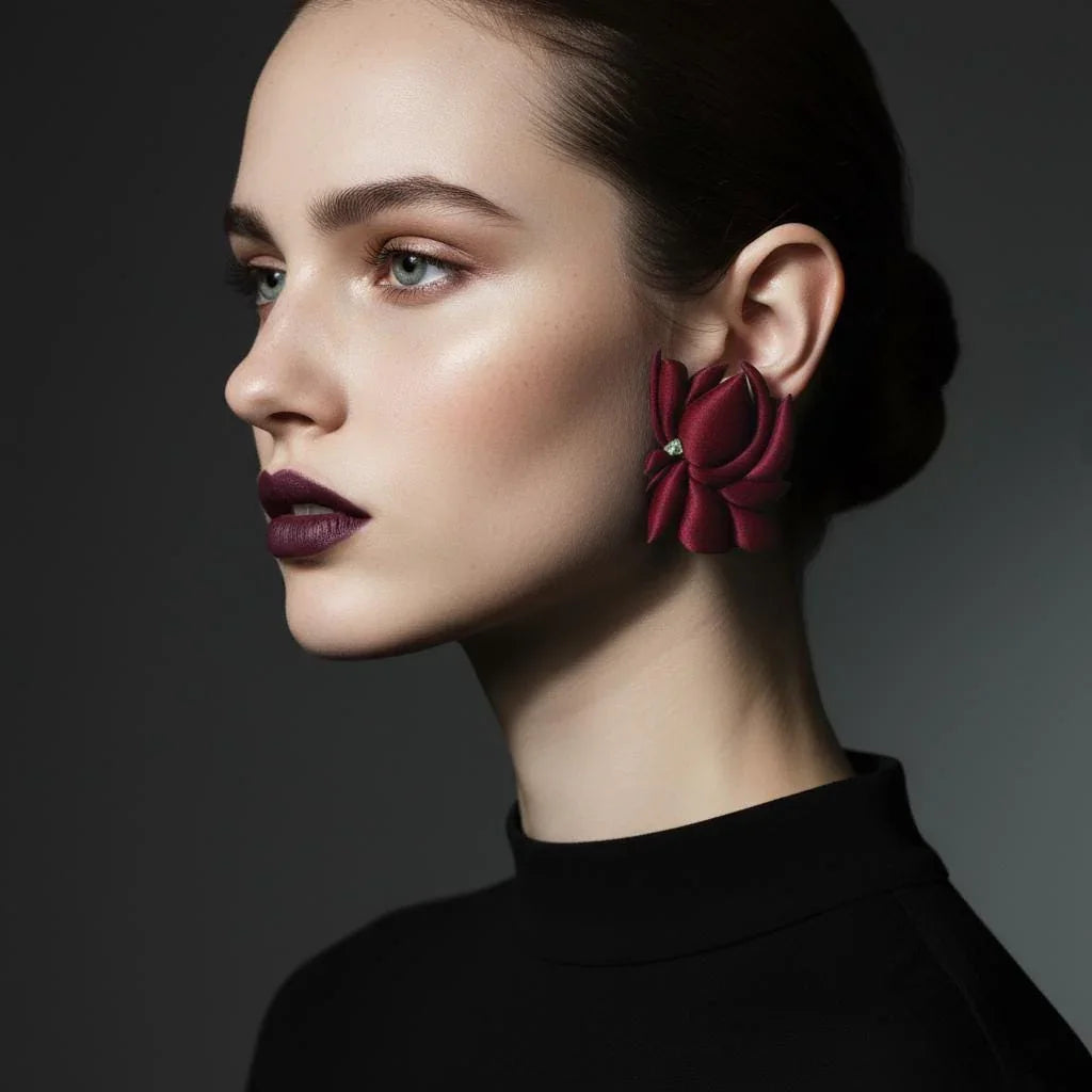 Woman wearing large burgundy flower-shaped statement earring, minimalist style