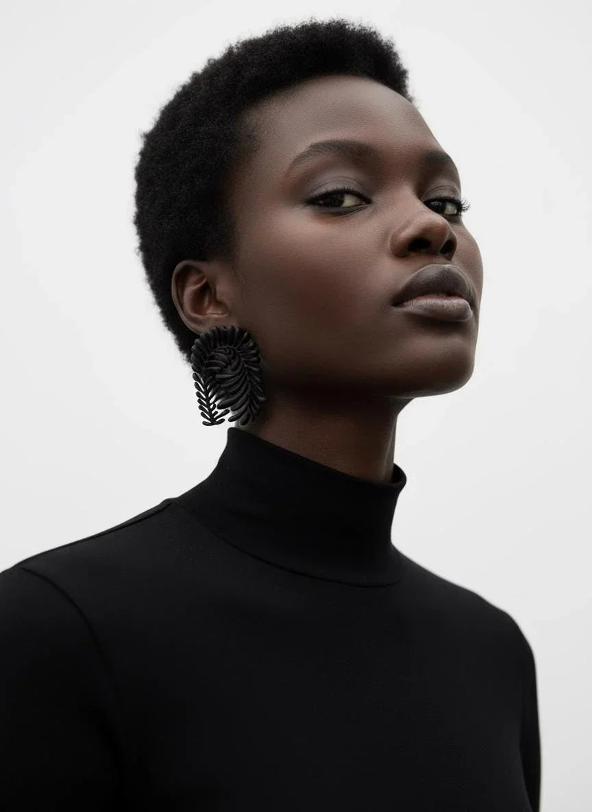 Model wearing black sculptural statement earrings and a black turtleneck top