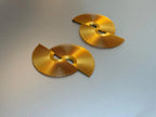 Gold fan-shaped statement earrings with geometric cutout design on a gray background