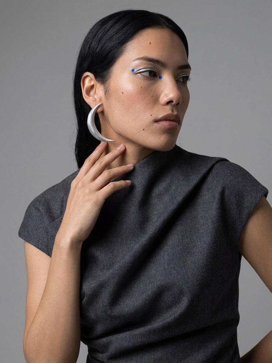 Boucles d’oreilles La Lune argentées en croissant, portées avec une tenue grise
