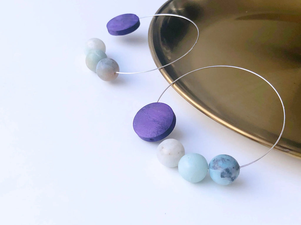 Artisan hoop earrings with purple disc and pastel gemstone beads on white background