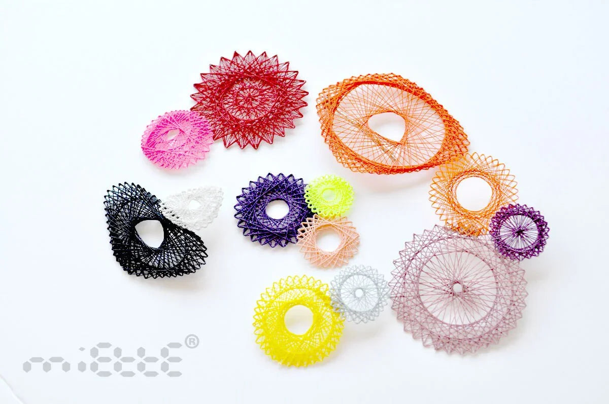 Colorful geometric lace brooches arranged on white background, handmade artistic jewelry
