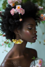 Woman wearing large yellow floral hoop earring and pink flowers in natural afro hair