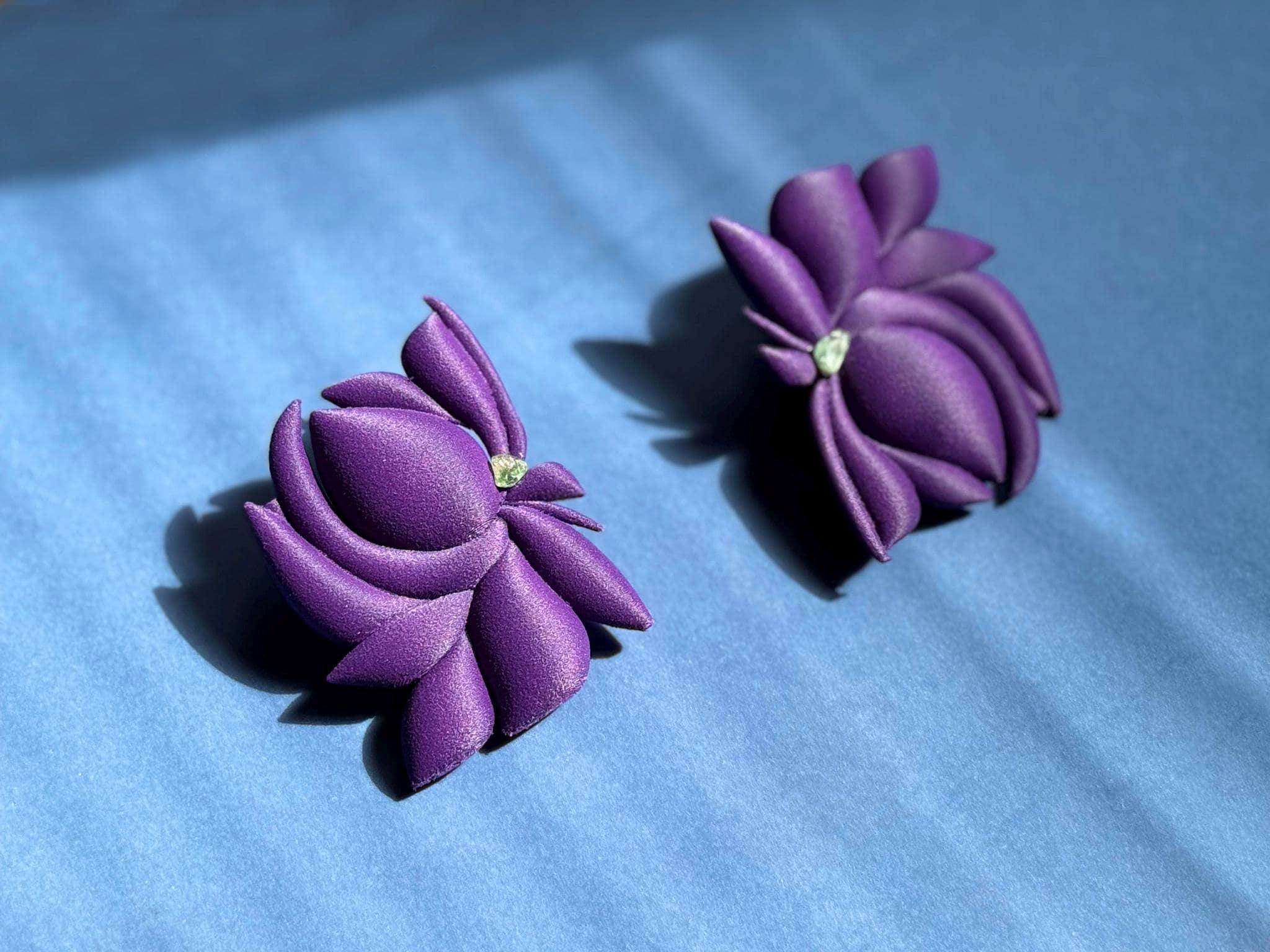 Artisanal purple flower-shaped earrings with textured petals on a blue background